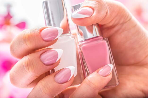 Trendy nail manicure. Woman hands holding nails polishes.