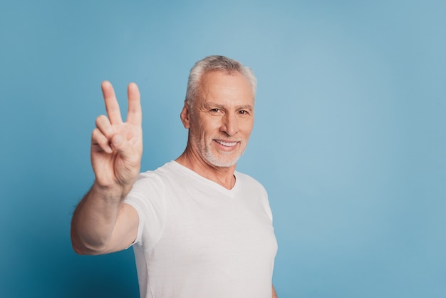 Trendy old man showing v-sign isolated blue background