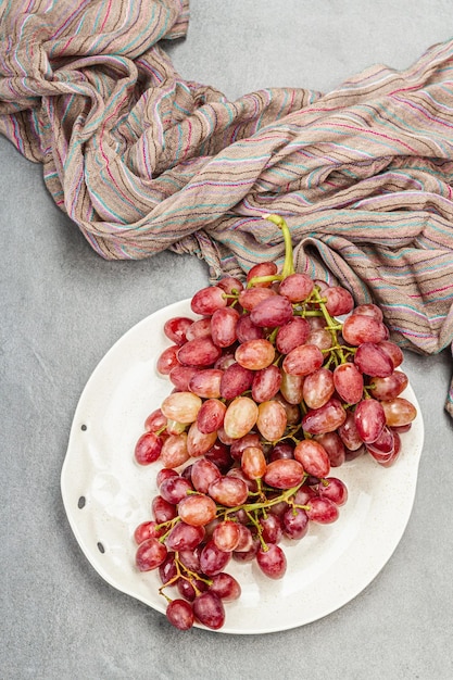 Trendy plate with a bunch of pink grapes Vintage textile napkin stone concrete background