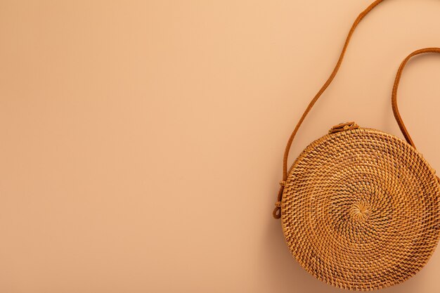 Trendy rattan bag on natural tone background. Female fashion Travel concept. Flat lay, top view, Trendy fashion style. Eco design.