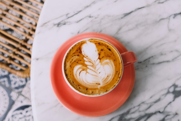 Trendy roze kopje warme cappuccino op marmeren tafel achtergrond mooie latte kunst op de top