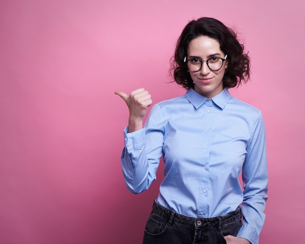 Trendy sexy young female wearing casual clothes posing over pink 