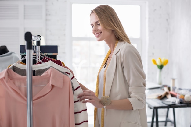 Trendy showroom. Vrij aardige onderneemster die kledingstuk op tribune berekent terwijl het glimlachen