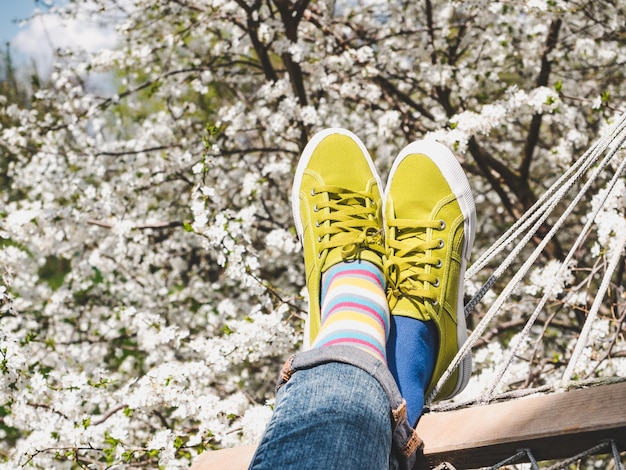 Trendy sneakers and colorful socks on the background of flowering trees Closeup outdoors Men's and women's fashion style Beauty and elegance concept