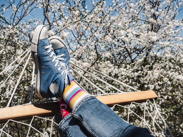 Trendy sneakers en lichte sokken op de achtergrond van een bloeiende boom. Detailopname. Heren- en damesstijl. Schoonheid, elegantie concept