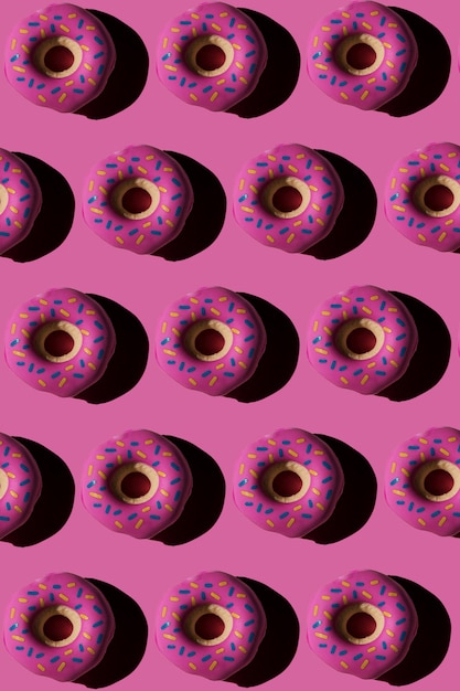 Trendy sunlight seamless pattern made of three colorful doughnut toys with sharp shadow on bright pink background Minimal food summer concept with copy spacexD