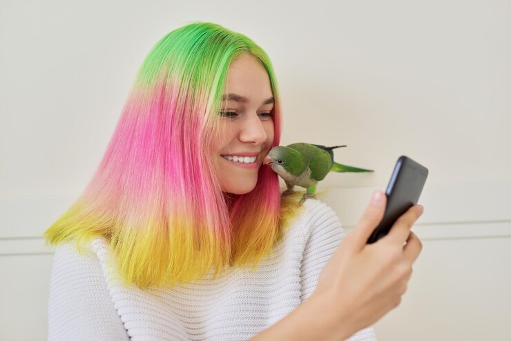 Фотография модная девочка-подросток со смартфоном и квакерским попугаем на плече