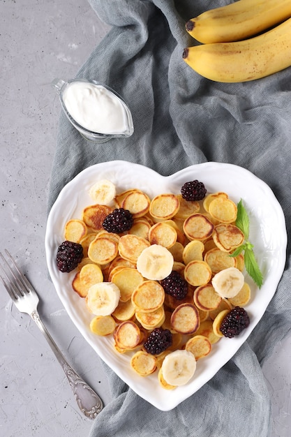 Trendy tiny pancakes with blackberry and banana in heart-shaped plate