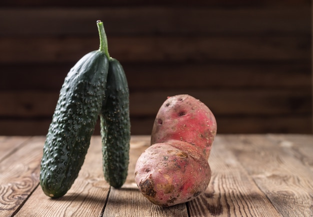 Trendy ugly organic cucumber, and potato on natural wooden table