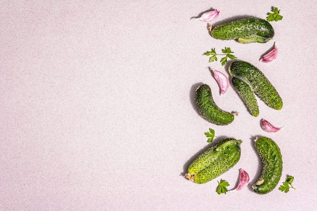 Trendy ugly organic vegetables. Fresh cucumbers, garlic cloves, parsley greens. Cooking ugly food concept, modern hard light, dark shadow. Stone concrete background