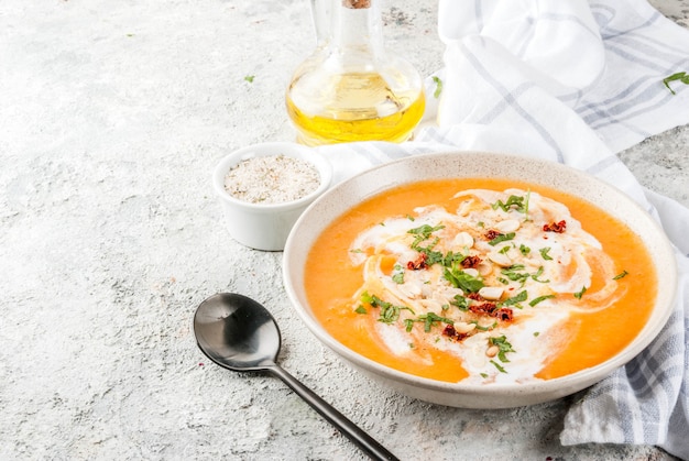 Trendy vegan food Sweet Potato Detox Soup with coconut milk dried tomatoes peanuts and herbs on grey stone table 