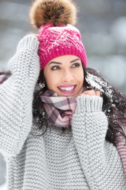 Trendy winter fashion outfit on a beautiful woman wearing\
sweater, scarf and pom pom hat.