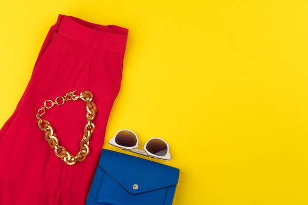 Trendy woman outfit with accessories on bright yellow background