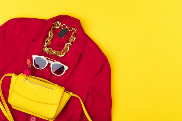 Trendy woman outfit with accessories on bright yellow background