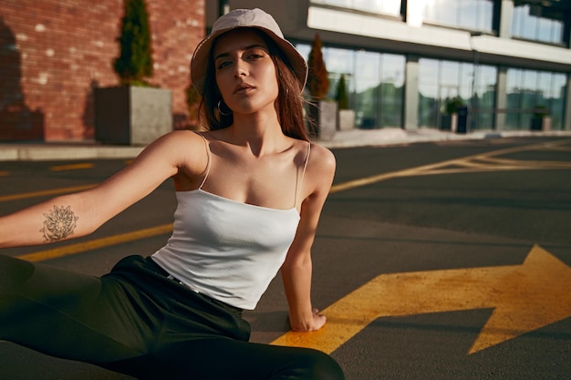 Trendy woman sitting on asphalt road