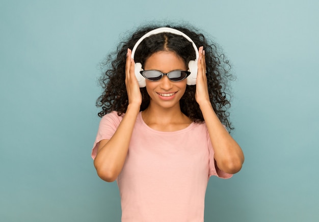 Trendy young African American girl wearing sunglasses and headphones