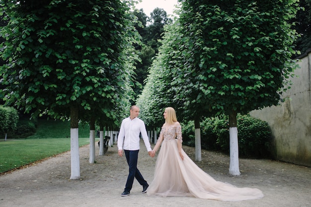 A trendy young couple walks in the city in summer, the young woman wears a luxury dress