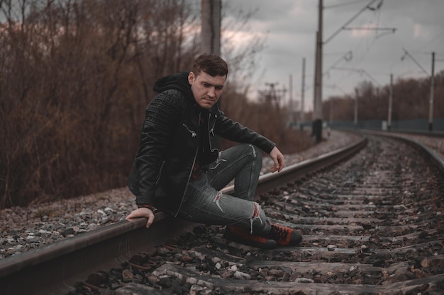 Trendy young man sitting on rails