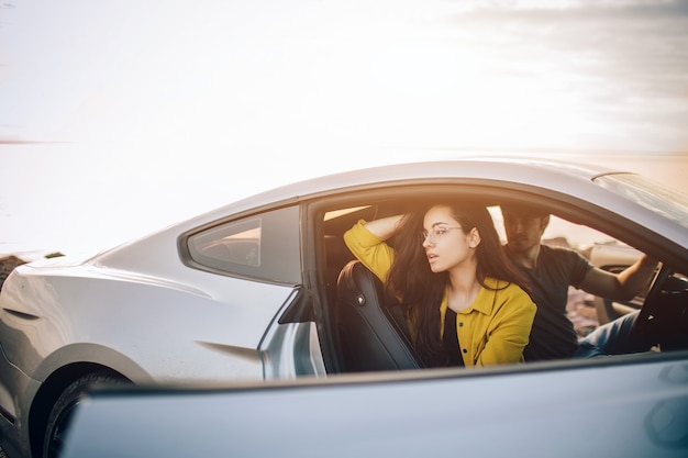 写真 トレンディな若い女性と車で旅行する男性。夏のロードトリップ旅行休暇でリラックスした幸せなカップル。