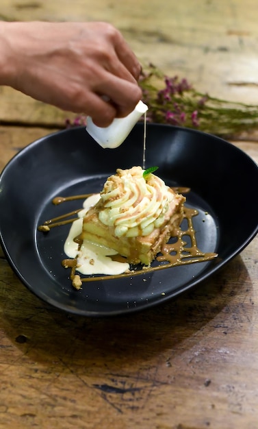 Tres leches cake or three milk cake in black plate on wooden table