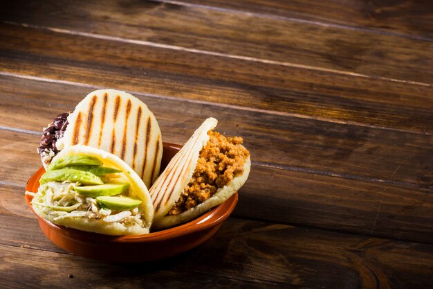 Tres tipos de arepas, comida latinoamericana en una mesa de madera