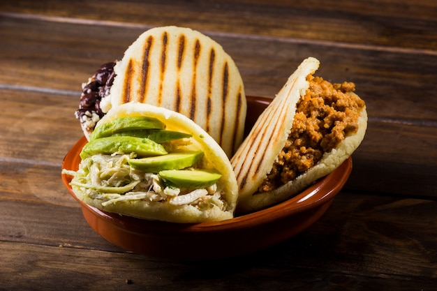 Tres tipos de arepas, comida latinoamericana en una mesa de madera