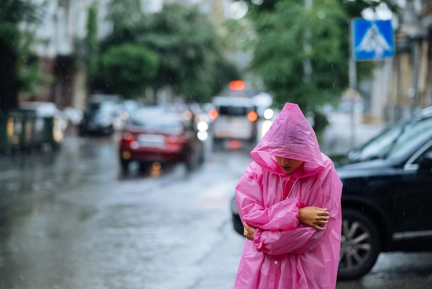 Treurige vrouw in een regenjas op straat in de regen