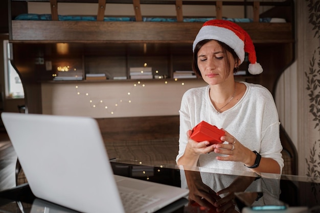 Treurige vrouw met een open geschenkdoos voor het computervideogesprek met familie of vrienden