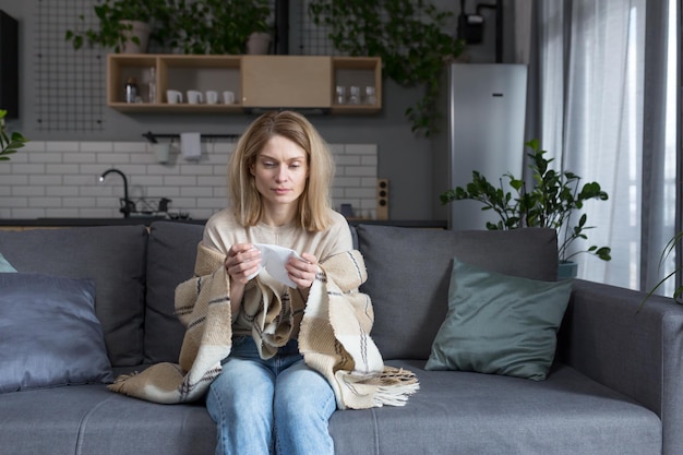 Treurige vrouw thuis zittend op de bank alleen in depressie huilen