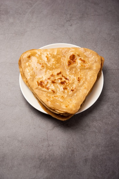 Triangle shape Plain Paratha or Parantha is yummy Indian flat-bread made of whole-wheat flour. served in a plate, selective focus