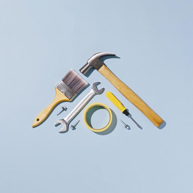 Triangular arrangement of hand tools over a blue background in a top down or flat lay view with copy space