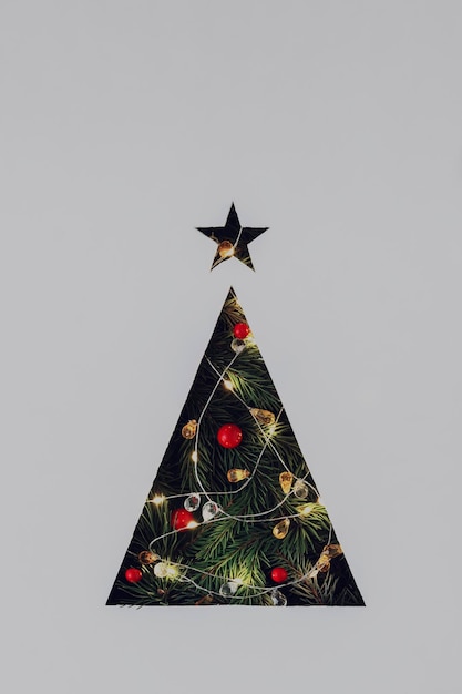 写真 ライト付きの花束とクリスマスツリーの枝が付いた灰色の紙板でカットされた三角形のクリスマスツリーは