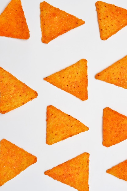 Triangular mexican corn chips scattered on white background