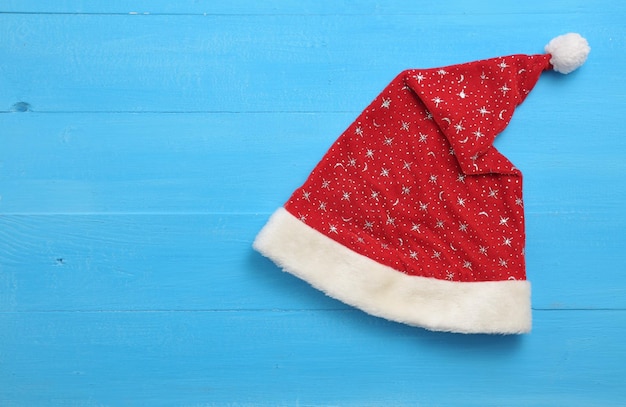 Triangular Santa Claus cap with stars on blue wooden background