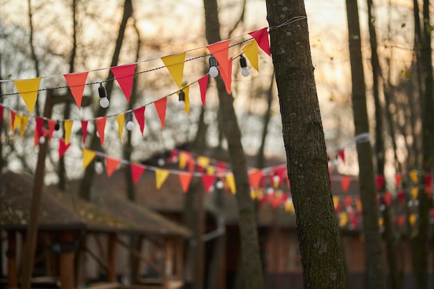 Bandiere triangolari gialle e rosse su una ghirlanda tra alberi bandiere triangolari colorate