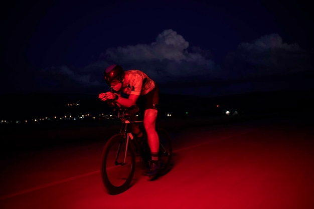 Фото Спортсмен по триатлону едет на велосипеде быстро ночью