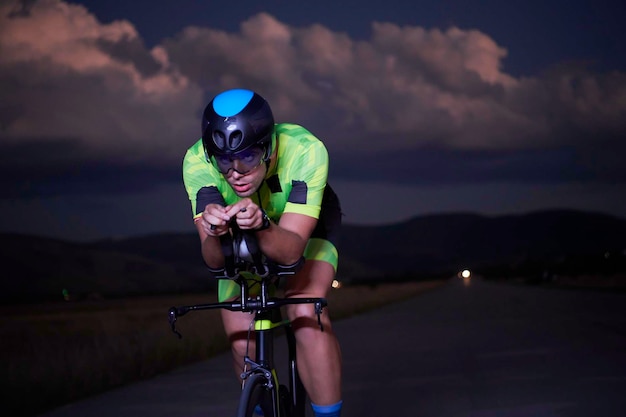 triathlon athlete riding bike fast at night