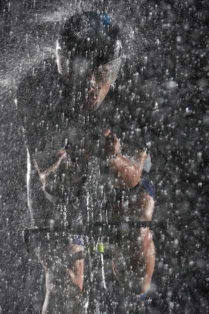 triathlon athlete riding bike fast on rainy night