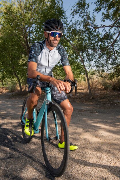 Triathlon atleet leunend op het stuur glimlachend met helm en zonnebril. Veiligheid