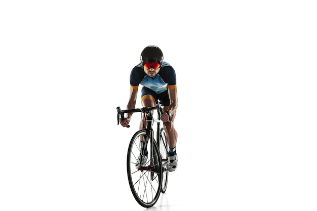 Triathlon male athlete cycle training isolated on white studio background. Caucasian fit triathlete practicing in cycling wearing sports equipment. Concept of healthy lifestyle, sport, action, motion.