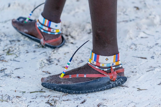 Tribal masai legs with a colorful bracelet and sandals made of car tires close up Island of Zanzibar Tanzania Africa