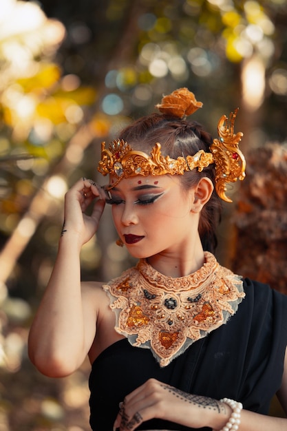 Tribal queen in makeup while wearing a gold crown and gold necklace with the black dress