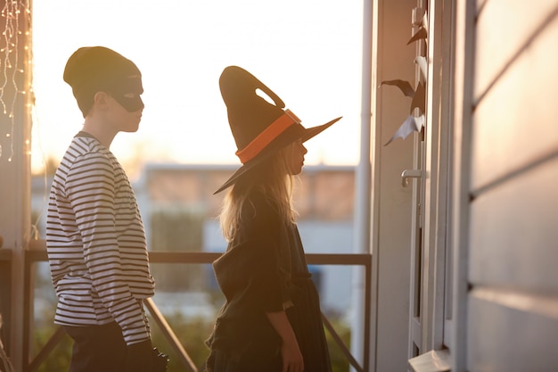 Trick or treat kids waiting by door op halloween