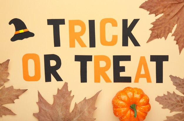 Trick or treat background with autumn leaves on beige. halloween concept