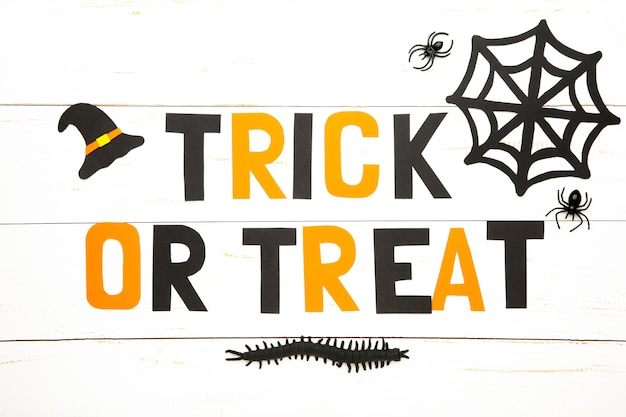 Trick or treat inscription with halloween decoration on white surface