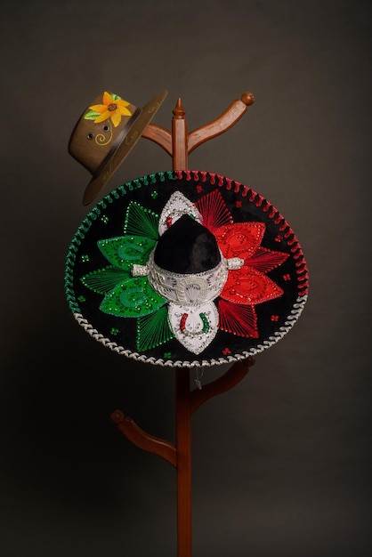 Photo tricolor charro hat and hand painted sombrero. mexican hats on a wooden coat rack.