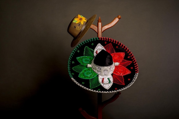 Photo tricolor charro hat and hand painted sombrero. mexican hats on a wooden coat rack.