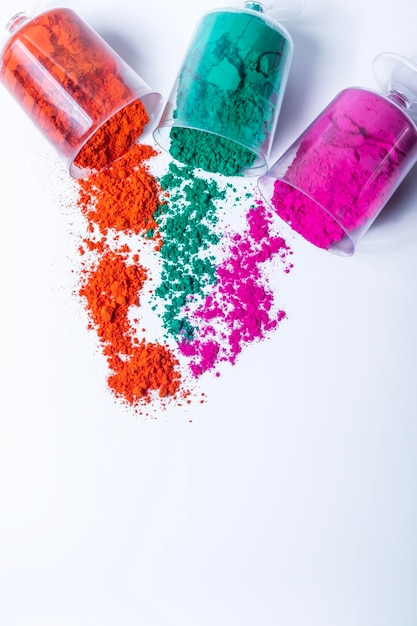 Tricolor Holi powder in plastic containers on white background