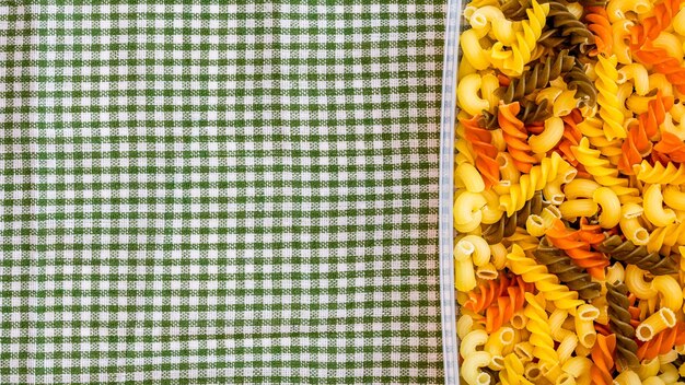 Foto tricolore fusilli pasta italiana cruda in contenitore di plastica da vicino isolata in composizione rustica