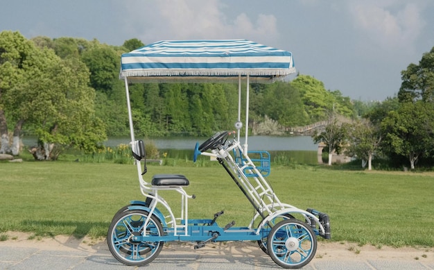 A tricycle with a blue canopy is parked in a park.